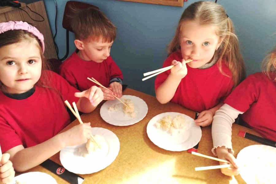 Dzieci jedzą chińskimi patyczkami