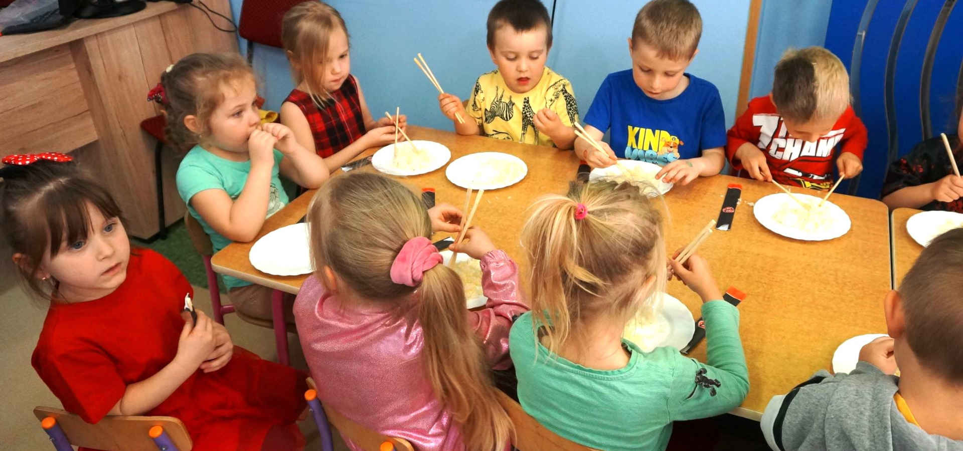 Dzieci jedzą chińskimi patyczkami