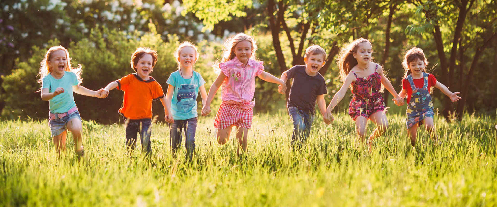 Dzieci biegną po zielonej trawie